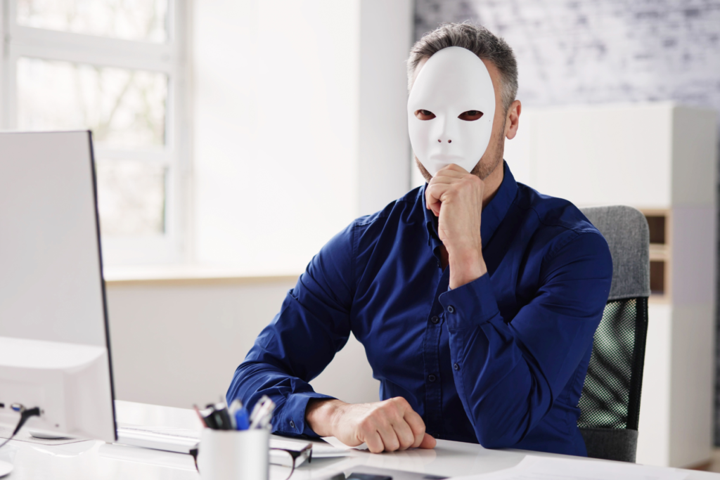 A person hiding behind a mask while working at a computer, representing the risk of an untrustworthy offshore staffing agency with no case studies
